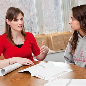 Counselor and student talking at table with papers on it