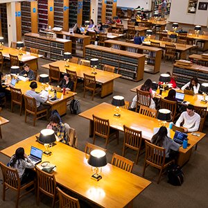 Wide view of students studying at tables in the College of Law library.
